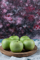 Apples in a wooden plate on the textured background