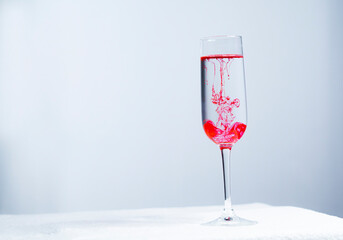 Red tattoo pigment dissolved in a glass of water. Hand stirring pigment in water