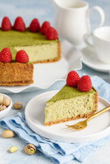 Cheesecake with pistachios and matcha tea decorated with fresh raspberries. Piece of cheesecake on plates