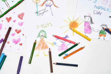 I love you, mom. Top view of beautiful colorful child drawings for mothers day and colored pencils on white background, handmade gift.