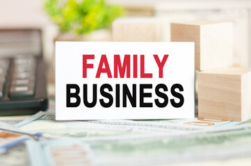FAMILY BUSINESS text on white paper, on the background of bills and wooden blocks, business concept