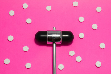 Neurological examination for women or the implementation of a neurological diagnosis by a female neurologist. The reflex hammer is on a pink background surrounded by white tablets