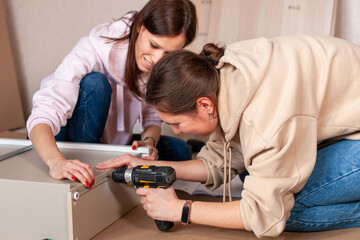 Women Assembling furniture from chipboard, using a cordless screwdriver