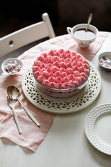 Fototapeta na wymiar Red currant tiramisu in a light bowl. Creamy pink dessert. White interior.