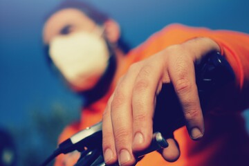 close up of a young man riding a bike wearing a surgical mask, concept of biking during Corona Virus