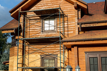 Modern wooden timber eco house villa facade during process of renovation, sanding wall for...