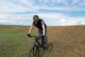 Fototapeta premium Sports brutal bearded guy on a modern mountain bike. A cyclist in a salt deserted place by the lake.