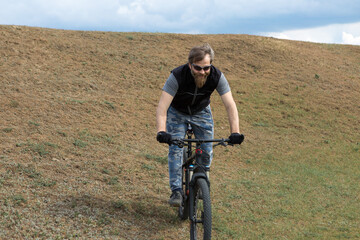 Sports brutal bearded guy on a modern mountain bike. A cyclist in a salt deserted place by the lake.