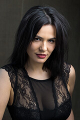 Portrait of a young sexy brunette girl in a lace top in dramatic tones. Vintage photo.