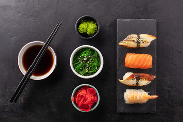 Sushi set on a slate board, soy sauce in a bowl, seaweed and ginger on the side. Japanese...