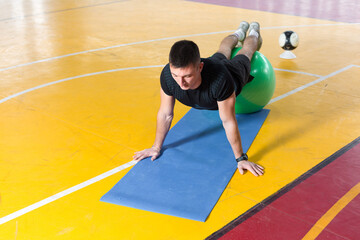Athletic guy in sportswear and fitness tracker doing exercises in gym.