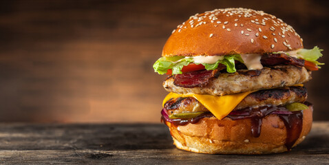 Yummy grilled chicken burger with double cutlet and cheese on a wooden table, copy space....