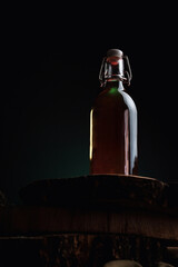 A glass of alcohol near a bottle. Old whiskey bottle on black wooden table. Drinks on a dark...