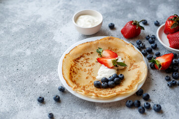 Pancakes with fresh strawberries and blueberries. National Russian cuisine, the holiday of Maslenitsa.
