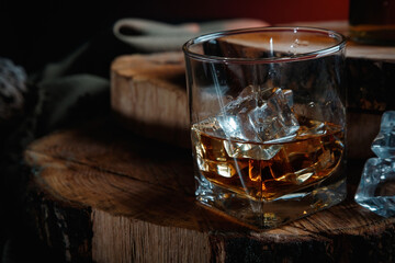 Glass of whiskey with ice on wooden surface
