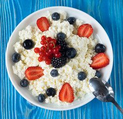 healthy breakfast cottage cheese with berries over blue wooden background, flat lay
