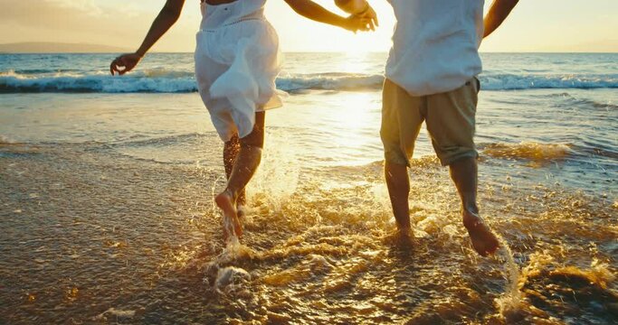 Happy couple in love, playing on the beach at sunset, splashing in the waves, travel vacation lifestyle, magical island paradise