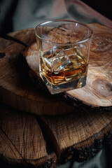 Ice cubes in a whiskey glass. Strong alcohol. Stand made of wood.