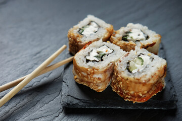 Sushi rolls with chopsticks on dark background