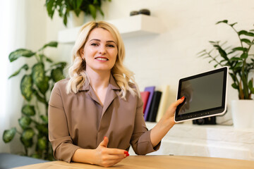 Caucasian woman smiling and showing the screen of her tablet