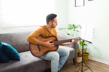 Attractive man playing his favorite song on the acoustic guitar