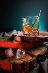 Glass of whiskey with ice on wooden surface