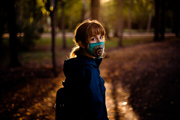 Woman with mask in a park at sunset