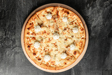 Hot tasty traditional italian pizza with salami, meat, cheese, tomatoes greens on a dark background