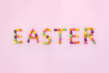 The word Easter made up of colored chocolate eggs. Minimal holiday concept.