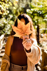 Woman holding a tree leaf covering her face