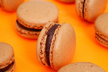 Homemade Chocolate cocoa macaron cookies filled with chocolate hazelnut ganache on an orange background
