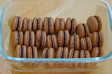 Homemade Chocolate cocoa macaron cookies filled with chocolate hazelnut ganache in a glass container