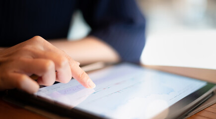 The female hand pointing on the stock trading graph for analysis about the trend of the stock that suitable for buy or sell.