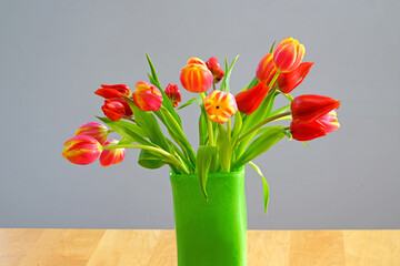 A vase of yellow and orange tulip flowers in a green vase