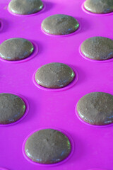 Homemade chocolate raspberry macaron cookies on a pink silicone mat on a baking sheet