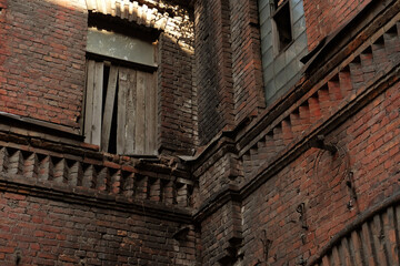 Brick facade of an abandoned old building with windows.