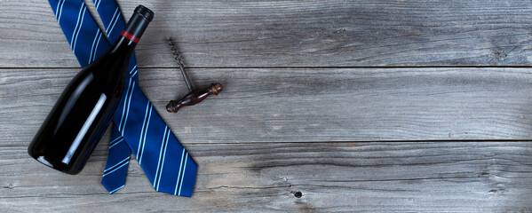 Blue striped tie plus a bottle of red wine and corkscrew on weathered wooden planks for Happy Fathers Day