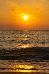 Yellow sunset from the low sun. Seashore with a sunset path on the waves.