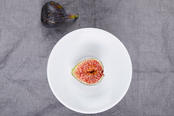 A plate of half and whole fig on grey background