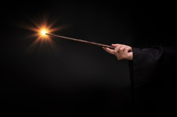 Fototapeta premium Magic wand with sparkle, Miracle magical wand stick with light sparkle. Teens hand holding a wand wizard conjured up in the air.