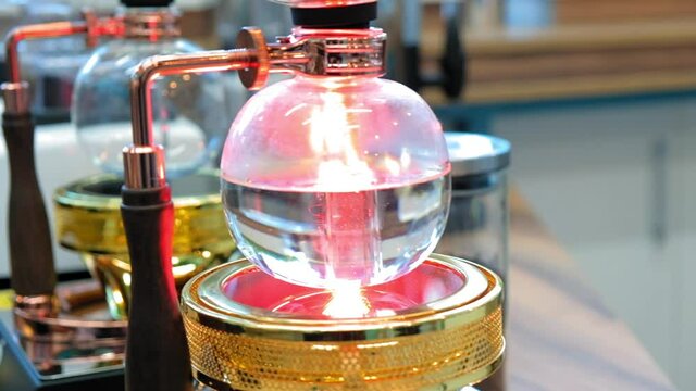 Beautiful coffee americano makes a barista in a gabe siphon in a cafe close-up, general plan