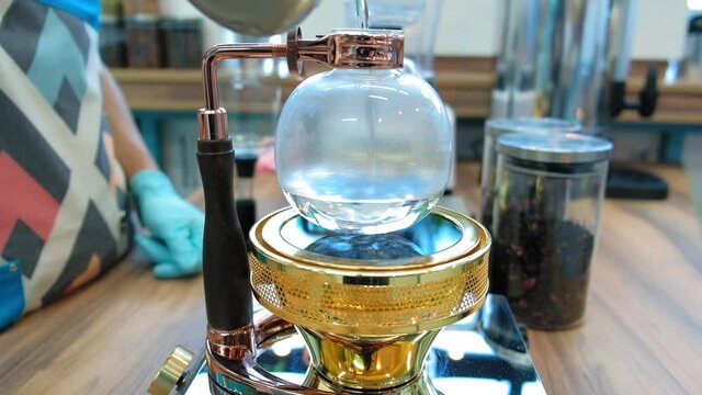 Beautiful coffee americano makes a barista in a gabe siphon in a cafe close-up, general plan