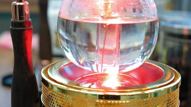 Beautiful coffee americano makes a barista in a gabe siphon in a cafe close-up, general plan