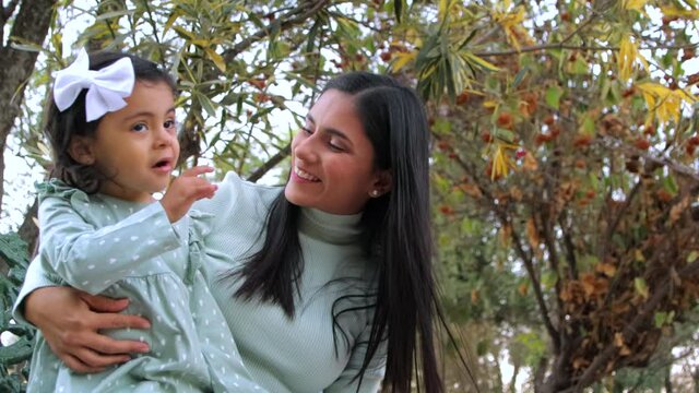 Madre habla con su hija sentadas en un parque