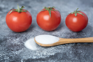 A wooden spoon full of salt with fresh tomatoes