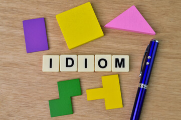 Square letters with text IDIOM over wooden background.