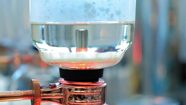 Beautiful coffee americano makes a barista in a gabe siphon in a cafe close-up, general plan