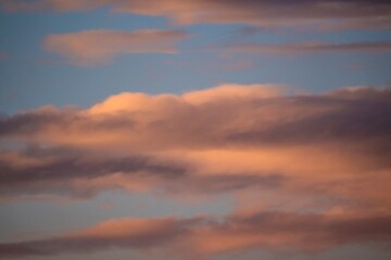 This photograph shows whimsical sunset clouds in a warm blue summer sky.