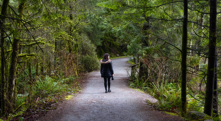 Girl Walking on a Beautiful Path in the Rainforest during a wet and rainy day. Lynn Canyon Park, North Vancouver, British Columbia, Canada. Nature Forest Background