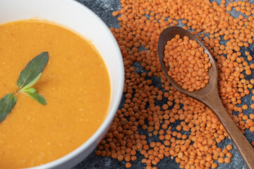 A white bowl of lentil soup with a wooden spoon